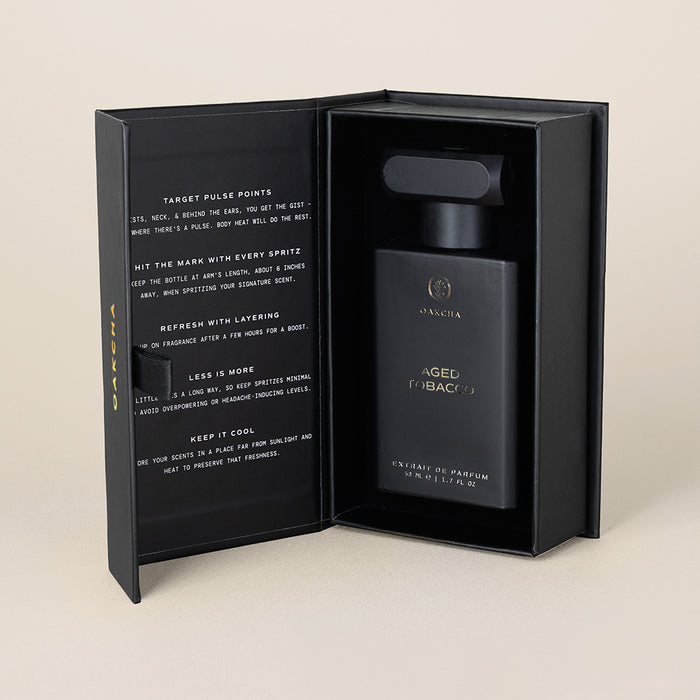Front view of Aged Tobacco 50ml perfume bottle showcasing matte black rectangular bottle with gold lettering inside open black presentation box