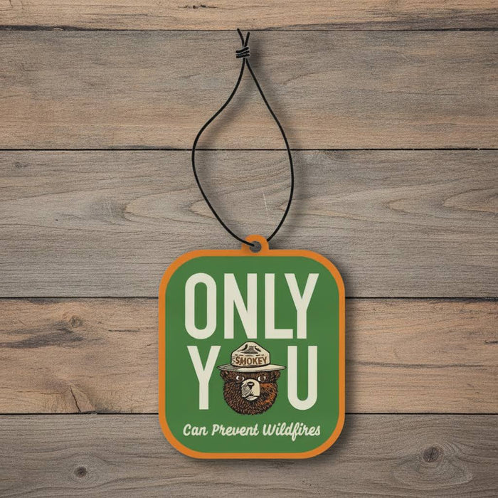 Forager Provisions LTD Smokey Bear hanging air freshener with spruce and cedar scent on a rustic wood background