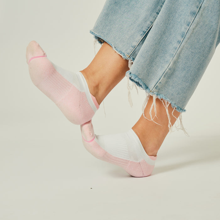 Ankle compression socks with a pink and white design, worn with frayed denim jeans.