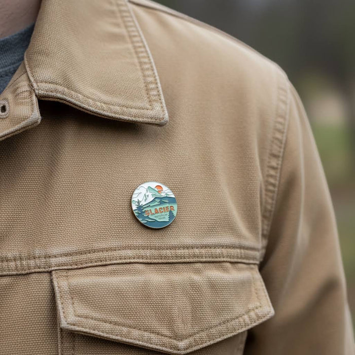 Forager Provisions LTD enamel pin featuring Glacier National Park art pinned to a tan canvas jacket