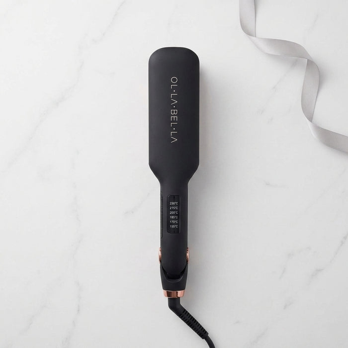 An Olla Bella 2" Wide Plate Flat Iron Hair Straightener with rose gold accents, shown from a top-down view on a white marble background with a white ribbon.