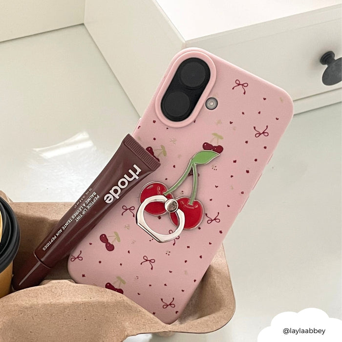 Pink phone case with cherry pattern, Coconut Lane cherry phone ring attached, nude lip balm, and a coffee cup.