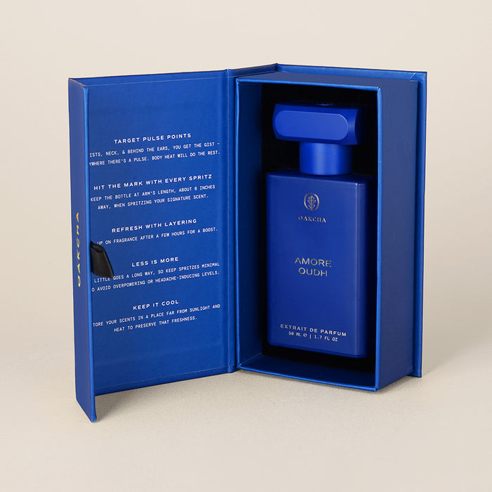 Front view of Amore Oudh 50ml perfume in blue presentation box, showing cobalt rectangular bottle and printed inner lid