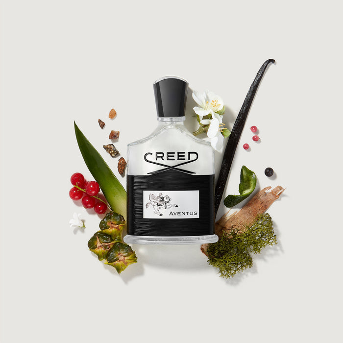 Creed Aventus bottle surrounded by natural fragrance ingredients including berries, vanilla, birch and florals | Creed Boutique