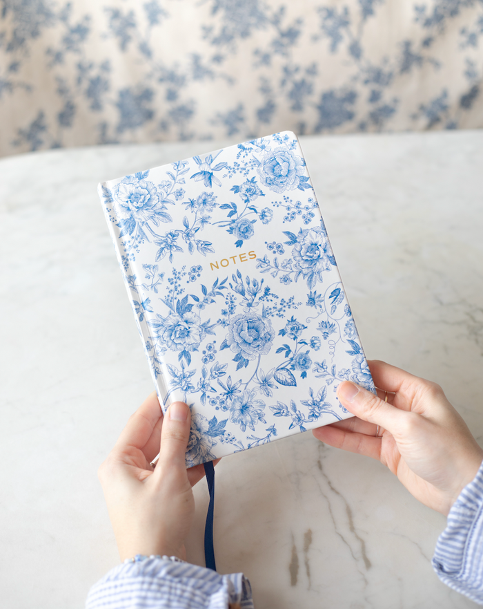 Notebook with blue and white floral pattern and gold details.