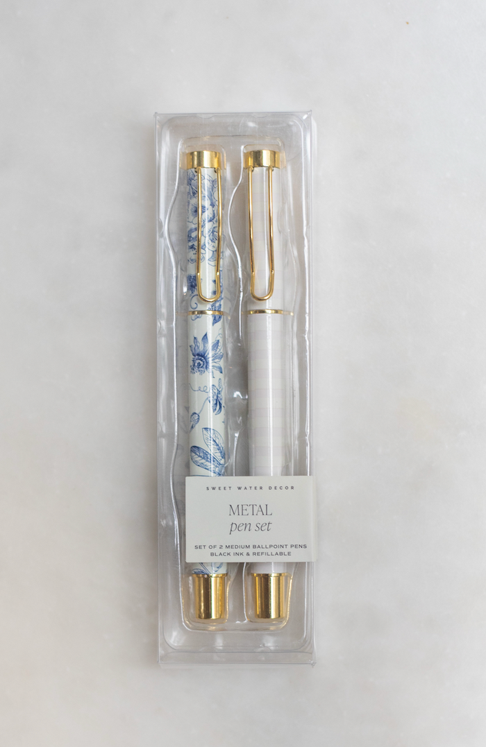 Packaged pen set with gold details, featuring one blue and white floral pen and one pink and white striped pen.