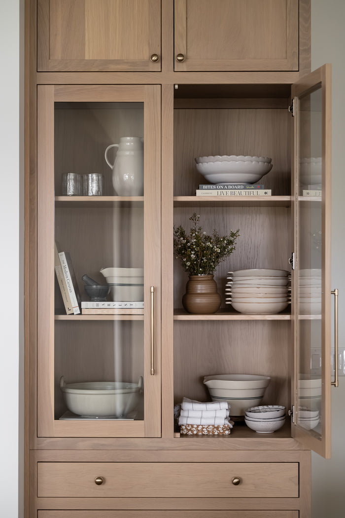 A brown, rounded ceramic vase with a slightly uneven rim and smooth, glossy texture styled on a shelf with florals and kitchenwares. The earthy tone and simple design suggest a rustic charm. | Wildwood Home Co.