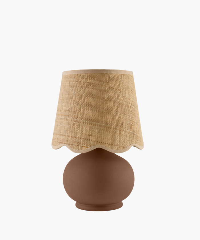 A table lamp with a textured, sand-colored shade and a round, matte brown base. The simple design conveys a warm and cozy feel.
