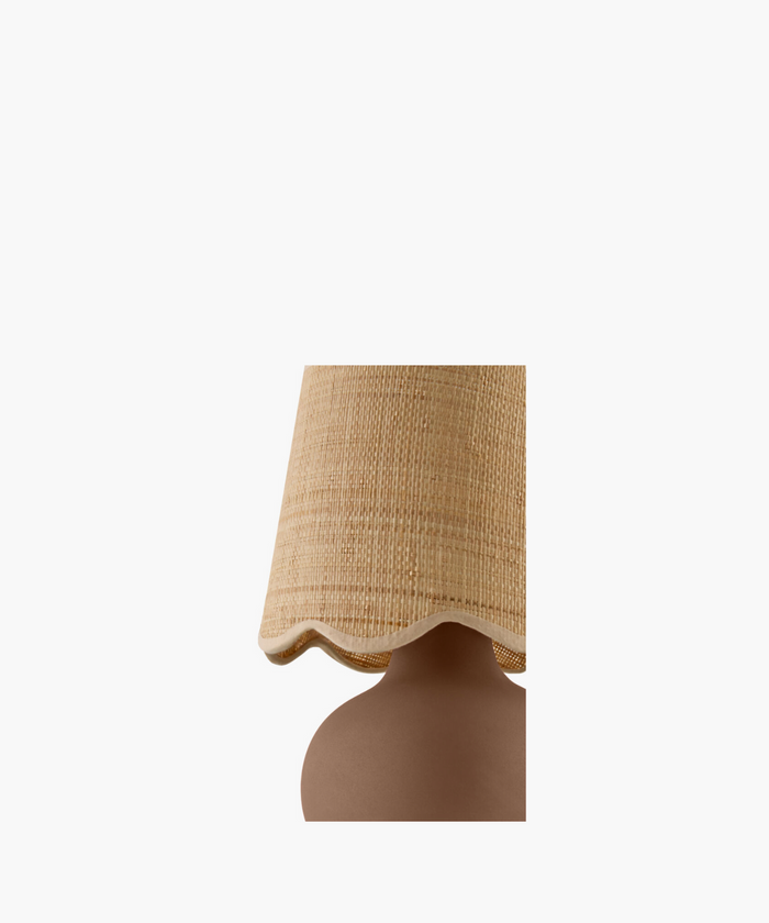 A table lamp with a textured, sand-colored shade and a round, matte brown base. The simple design conveys a warm and cozy feel.