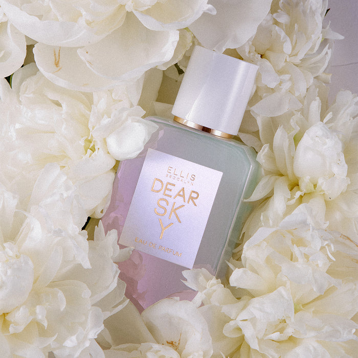 Dear Sky 50ml Eau Dr Parfum surrounded by white flowers, on white background.