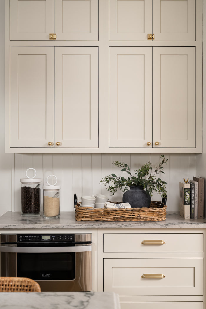 A large, round, weathered gray clay vase with a narrow neck styled with greenery on a kitchen counter.  | Wildwood Home Co.