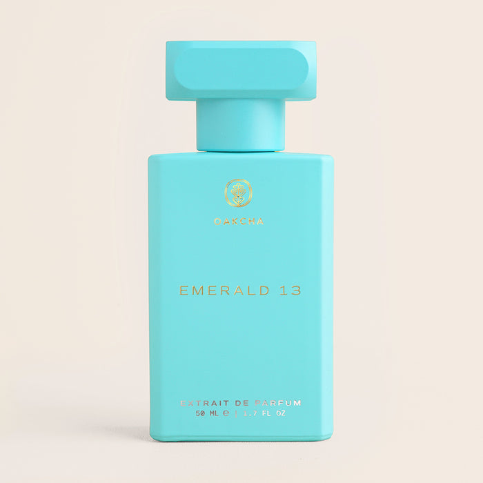 Front view of Emerald 13 perfume bottle showcasing turquoise rectangular bottle with matching cap and gold lettering on a neutral beige background