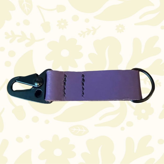 Purple Kjøtt Forager Provisions Leather Key Fob with metal ring and clasp, displayed on floral background for style.