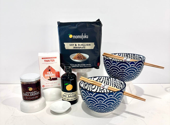 Momofuku soy and scallion noodles package with bowls, chopsticks, and other items on a white background