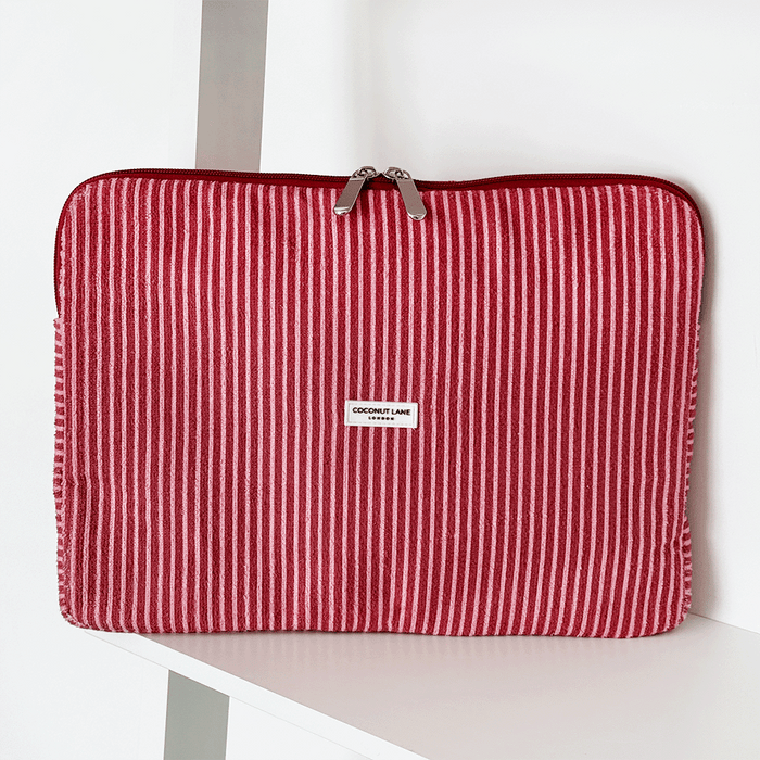 Red and white striped laptop sleeve with zipper, standing upright on a white shelf.