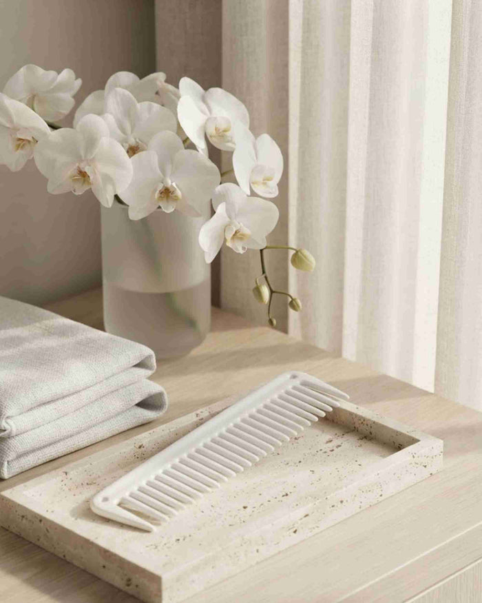 White cutting comb with fine teeth lying on a light countertop