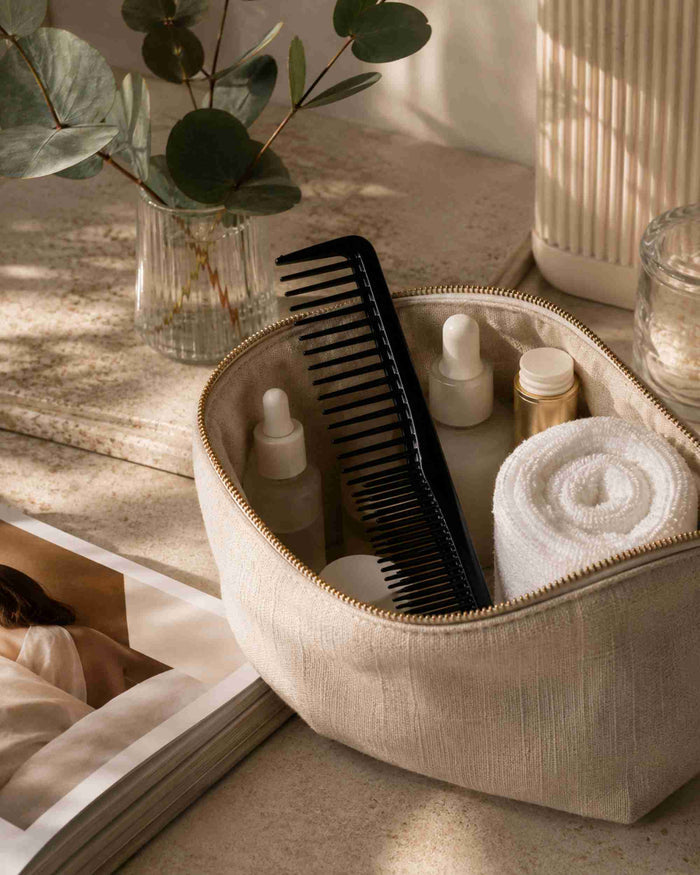 Black fine-tooth styling comb with wide teeth, shown in a zip pouch.