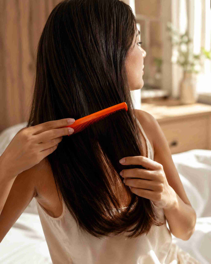 Orange fine-tooth comb used to detangle smooth hair at the shoulders