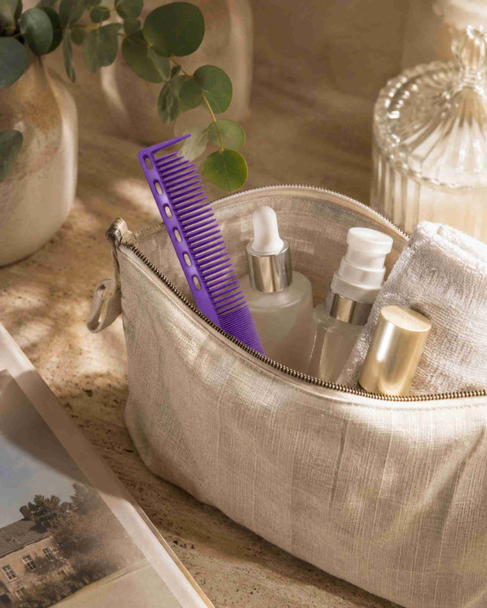 Purple sectioning hair comb inside a beige zippered pouch with hair-care bottles
