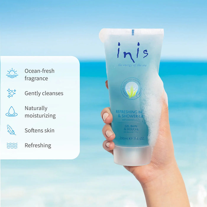 Hand holding a blue tube of Inis refreshing shower gel with ocean view in the background