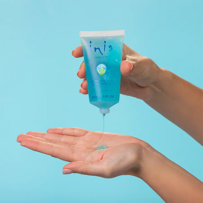 Hand holding a blue tube labeled 'inis' with a small amount of product on a light blue background