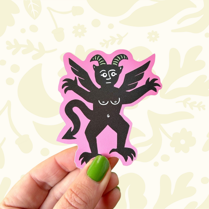 Forager Provisions LTD pink devil vinyl sticker with a black medieval marginalia creature design on a colorful desk