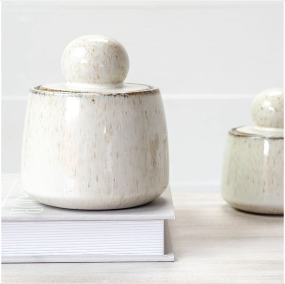 Two ceramic jars with lids on a light wooden surface. | SW Home