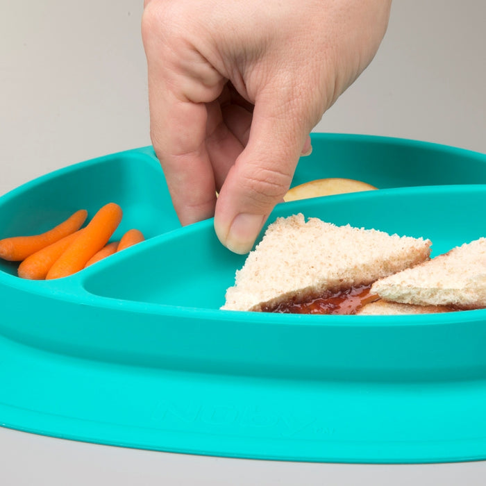 A hand reaches for a sandwich triangle on the Sure Grip Miracle Mat 3-Section Plate, which also holds baby carrots and apple slices—perfect baby tableware for little ones.