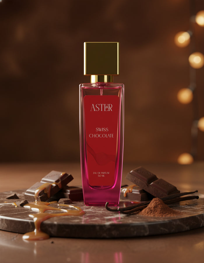 Pink perfume bottle labeled 'Aster Swiss Chocolate' on a decorative stone surface with chocolate and vanilla beans.