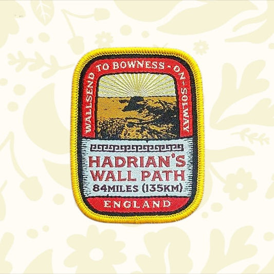 Hadrians Wall Path patch with sunset graphic and England text displayed on wood—Adventure Patch Company collectible badge.