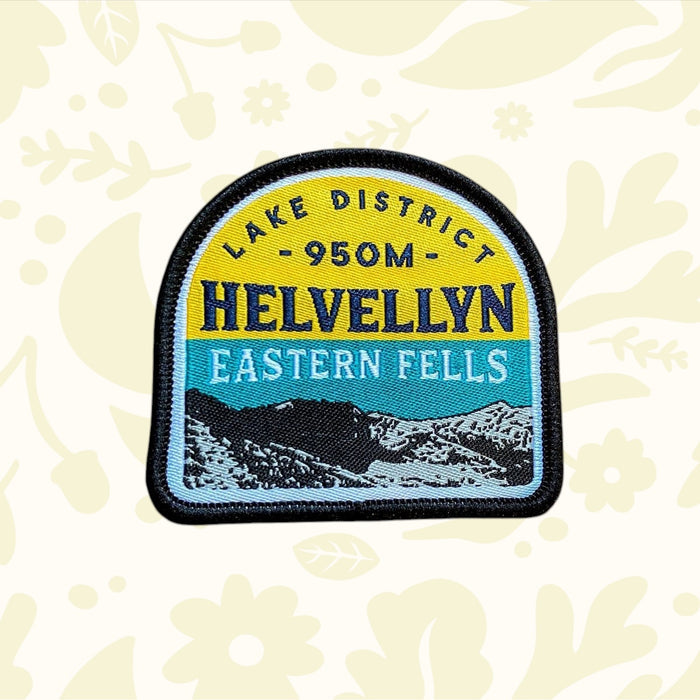 Helvellyn Patch by The Adventure Patch Company with Eastern Fells mountain design, displayed on wood background. Outdoor gift.