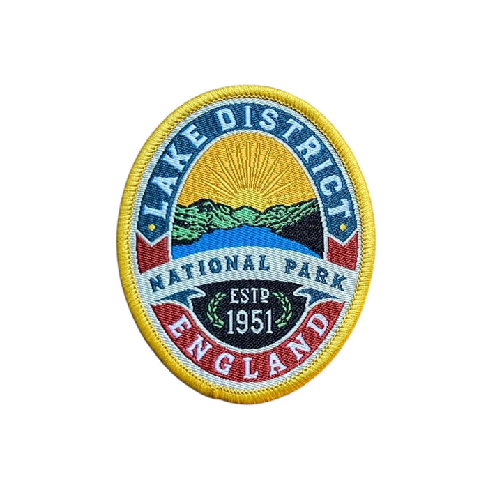 Forager Provisions LTD Lake District National Park embroidered patch featuring hills, lake, and sun on a wooden surface.