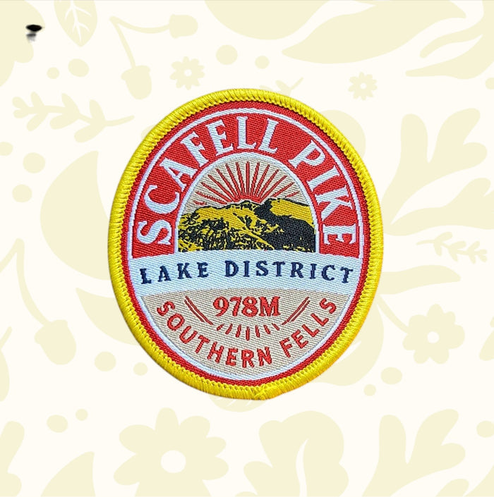 The Adventure Patch Company Scafell Pike Fells Series patch, 978M Lake District, displayed on wood surface. Hiking souvenir.