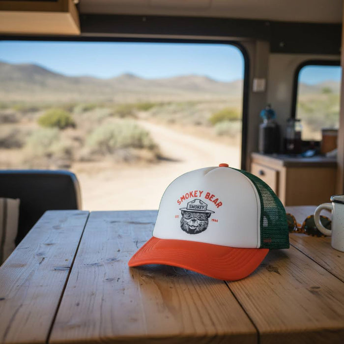 Forager Provisions LTD Smokey Bear varsity foam trucker hat with green mesh back and orange brim on a wooden table