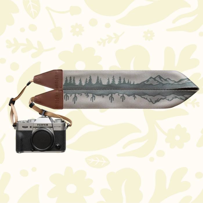 Wildtree camera strap with cacti, tree, mountains on floral backdrop, styled with camera. Best DSLR accessory 2024.