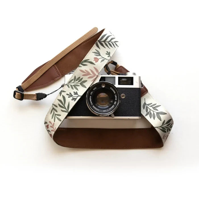 Stylish camera with Wildtree Moody Flower strap and brown leather accents on white background, perfect camera accessory.