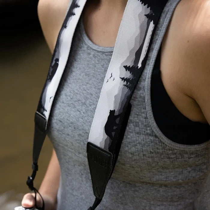 Person in gray tank top wearing Wildtree Wildlife Camera Strap by Wildtree, standing outdoors, wildlife photography gear.